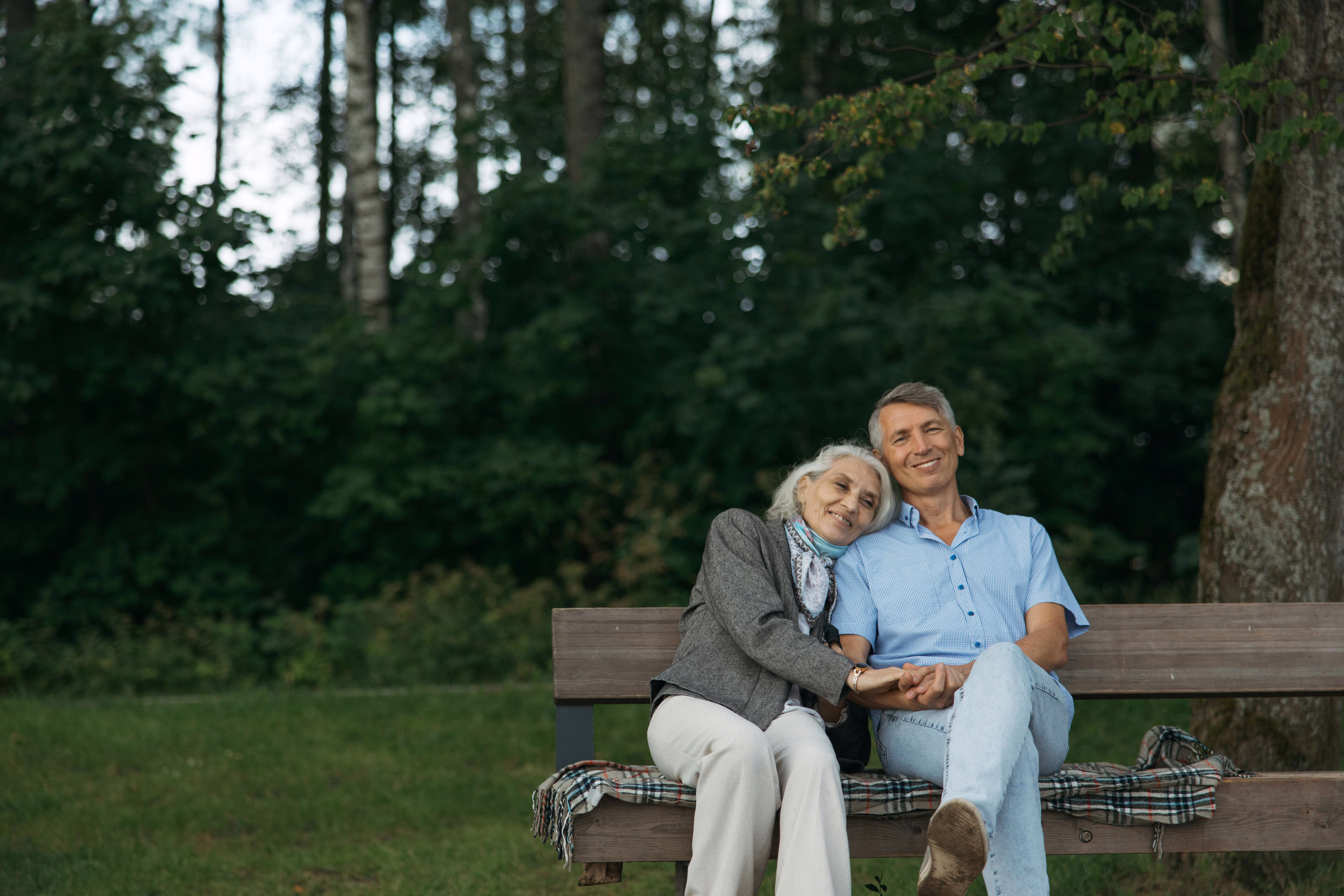Happy senior couple sitting on a park bench enjoying retirement together